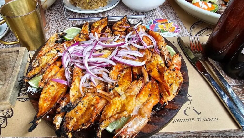 Platillo de mariscos al carbón con rodajas de cebolla morada y una pieza de limón