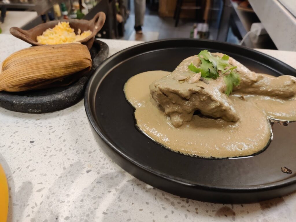 Platillo de mole verde con una pieza de pollo, con un tamal y arroz