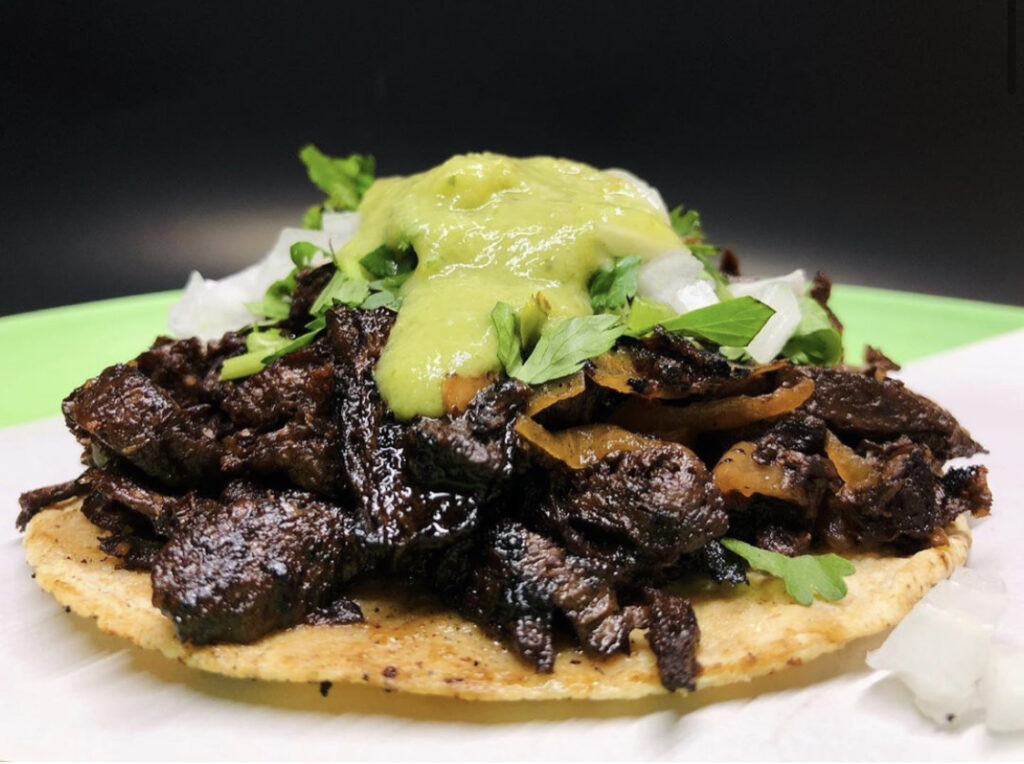 Taco vegetariano con cebolla y cilantro con salsa verde encima