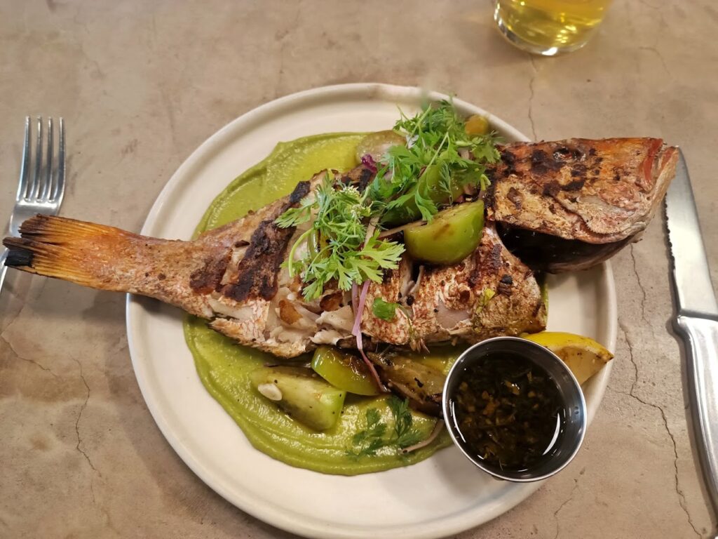 Pescado bañado en salsa verde con vegetales frescos y unas hojas de cilantro