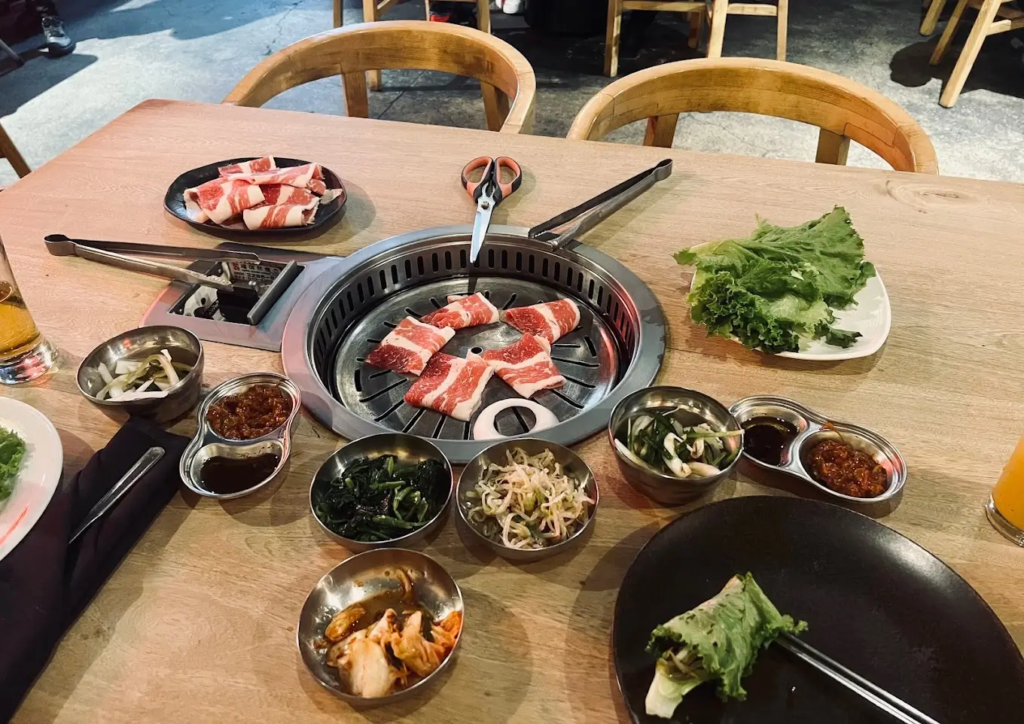 Asador de carne en la mesa con variedades de vegetales y carnes