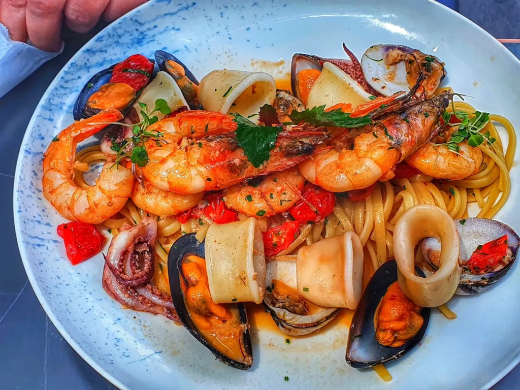 Platillo de mar con opciones de mariscos, camarones y conchas, acompañados de vegetales