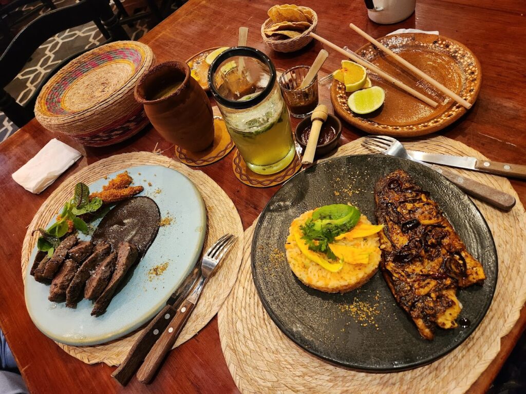 Mesa con variedad de platillos como carnes, pesacos y otras bebidas