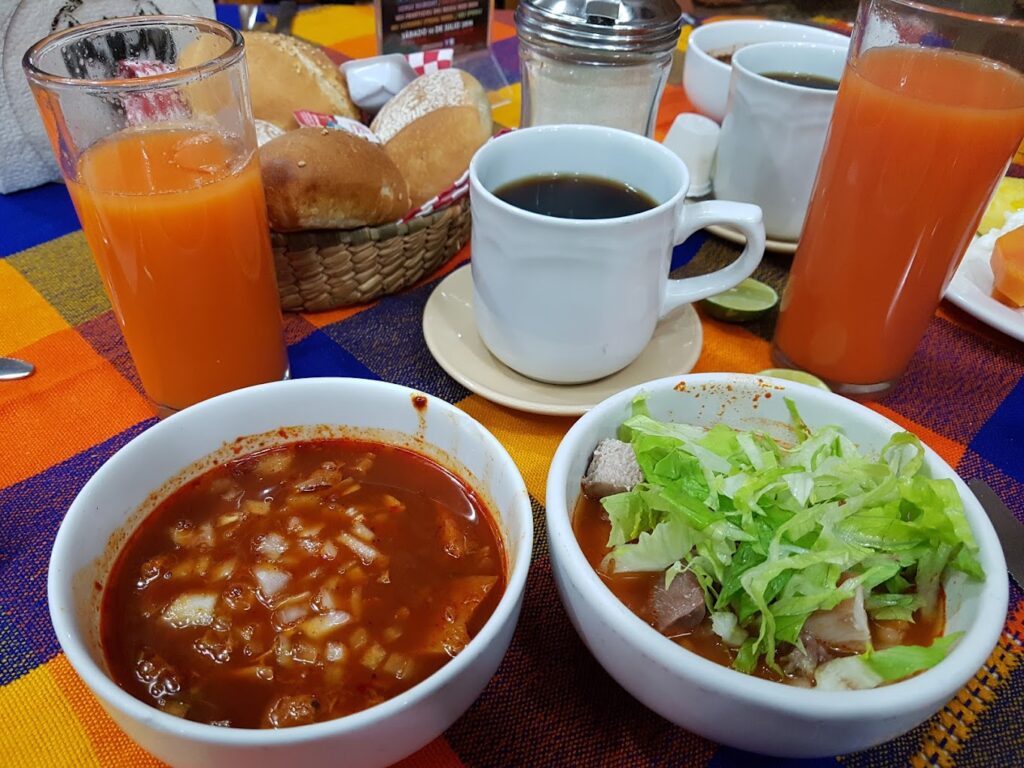 caldo rojo acompañado de verdura y una tasa de cafe con jugo color naranja