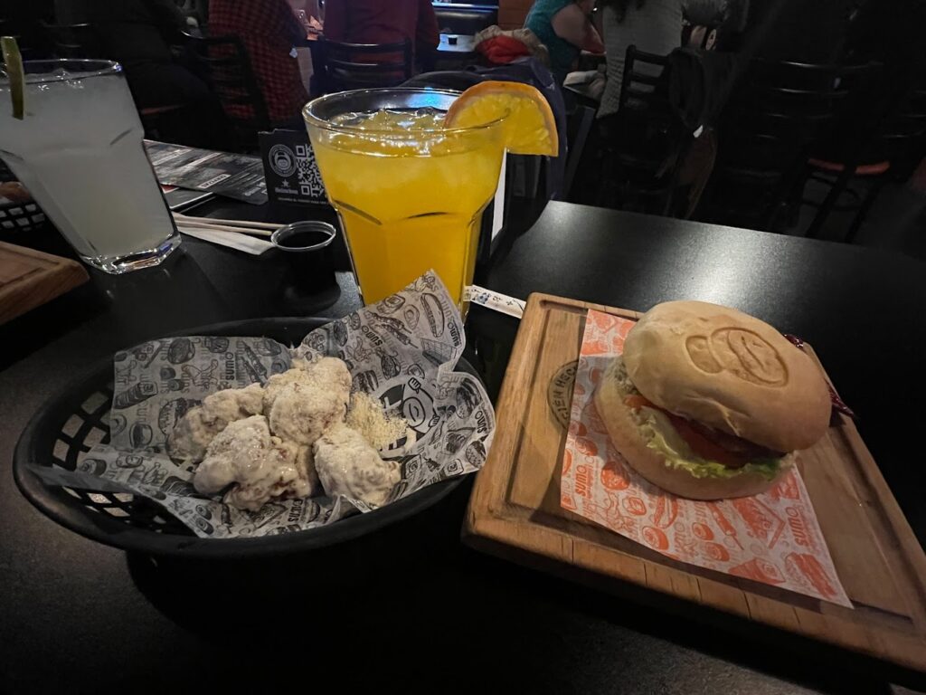 hamburguesa clasica acompañada de alitas y una bebida color naranja